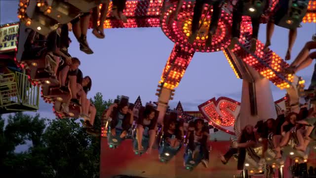 Rack focus shot of a carnival ride slowly coming to a stop.
