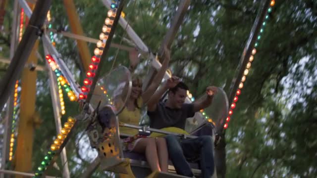 Ferris-wheel riders excitedly hold their arms up as they circle down