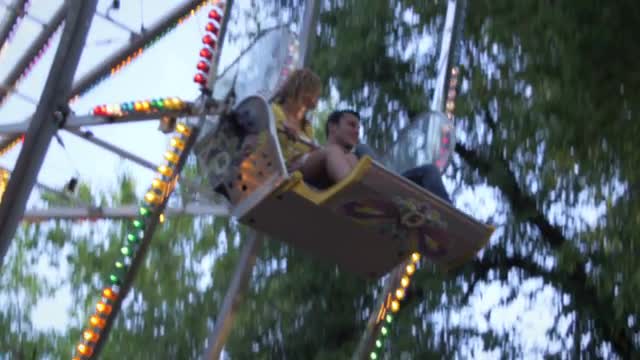 Ferris-wheel riders smile as they circle up