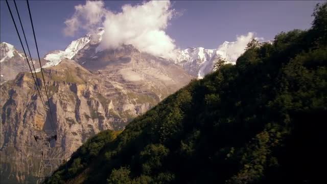 Tracking shot of the Swiss alps and the aerial tramway cables