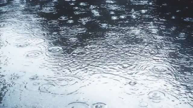 Rain falling on pavement in slow motion.
