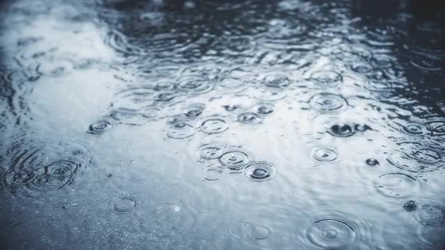 Rain falling on pavement in slow motion.
