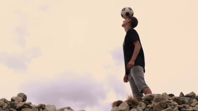 Young man balancing a soccer ball on his head.