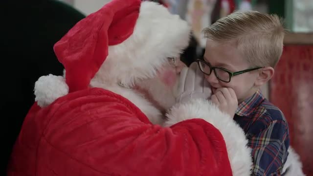 Boy whispering into Santa's ear