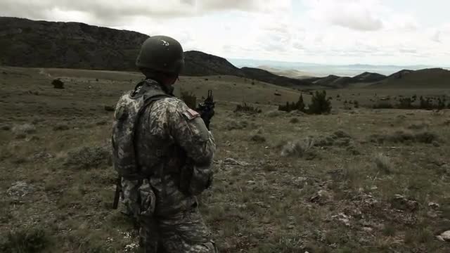 Soldier firing 40 mm grenade launcher attached to M4 assault rifle while standing.