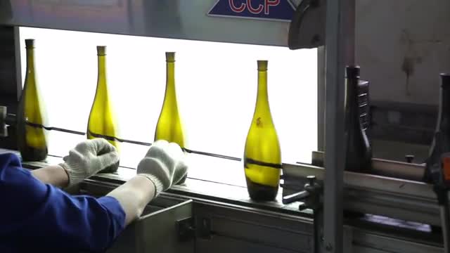 Worker checks quality and purity of glass bottles