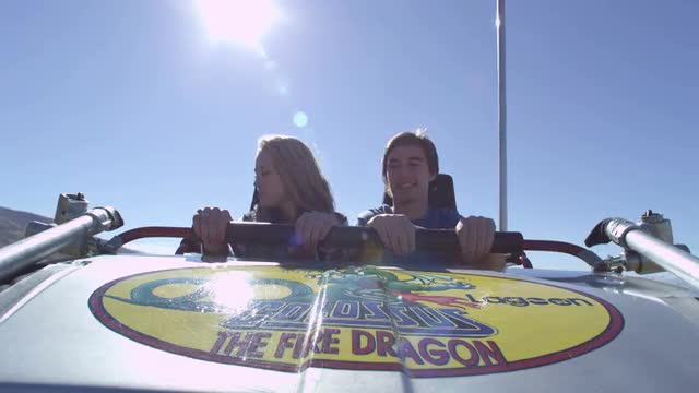 Slow motion shot looking at a couple riding a rollercoast.