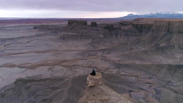 Aerial view flying past woman stilling on rocky point