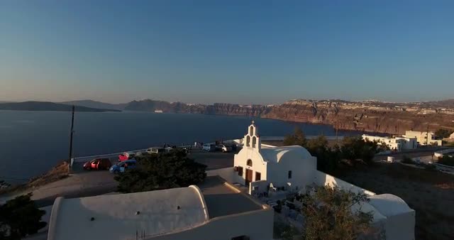 Aerial shot over Santorini church at sunset with sea and amazing landscape in view