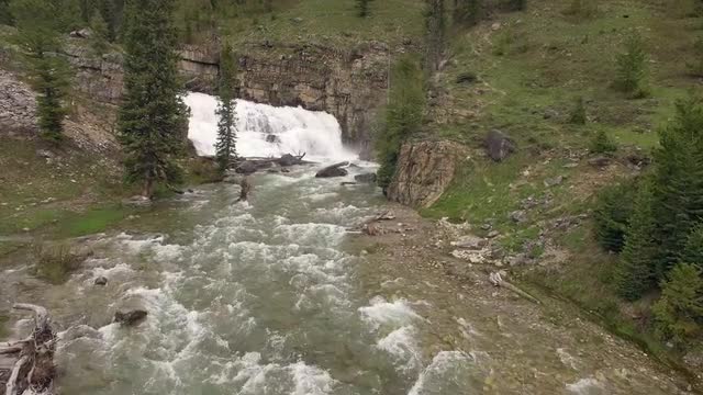 Flying over river towards waterfall in the Wyoming mountains