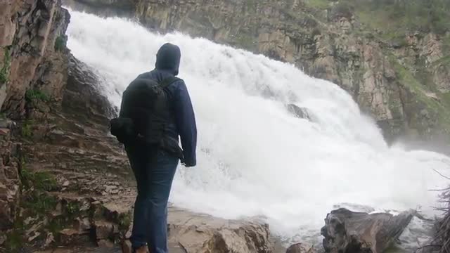 Woman hiker standing in front of waterfall