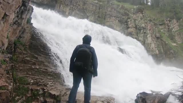 Slow motion of woman hiking towards waterfall