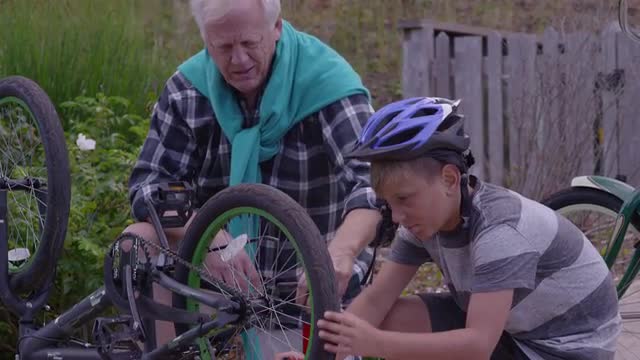 Senior man and grandson fixing bicycle together