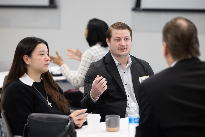 Photo of three individuals having a discussion at a table
