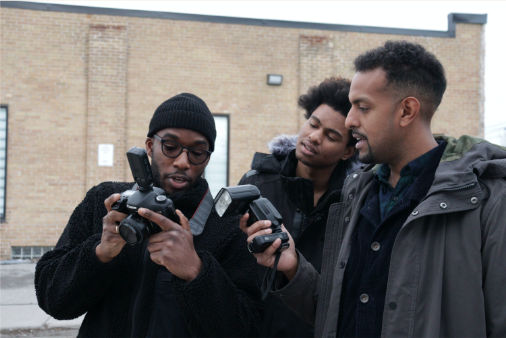 Trois hommes qui manipulent un appareil photo et un flash