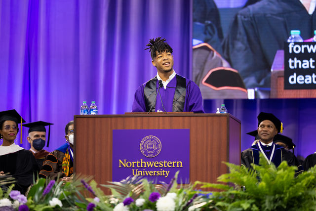 Adorned in a purple graduation gown, alumnus Jay Towns stands at a podium and delivers the 2022 School of Communication Convocation speech.