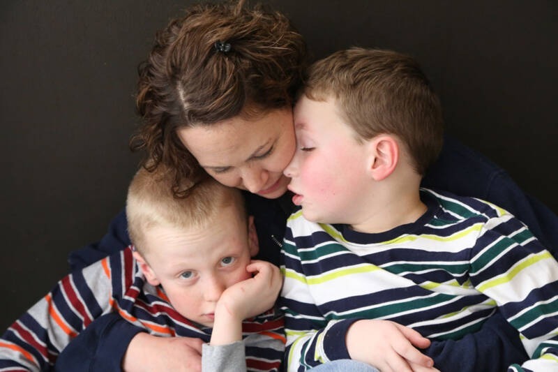 A person hugging two boys AI-generated content may be incorrect.