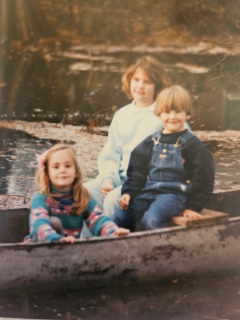 A group of children sitting in a boat Description automatically generated
