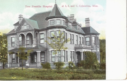 A large grey building with a black fence Description automatically generated