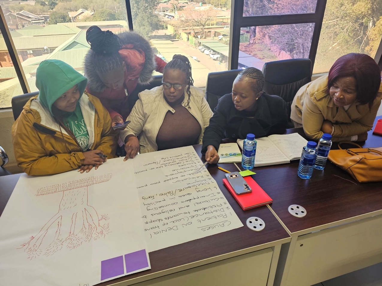 A group of people sitting at a table looking at a large piece of paper AI-generated content may be incorrect.