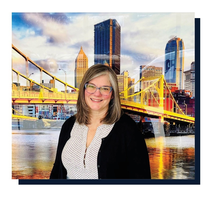 Lisa Kolodziejski standing in front of a bridge with a city skyline in the background.