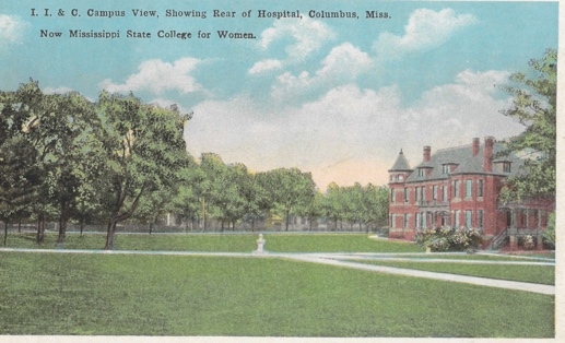 A large brick building with trees in front of it Description automatically generated