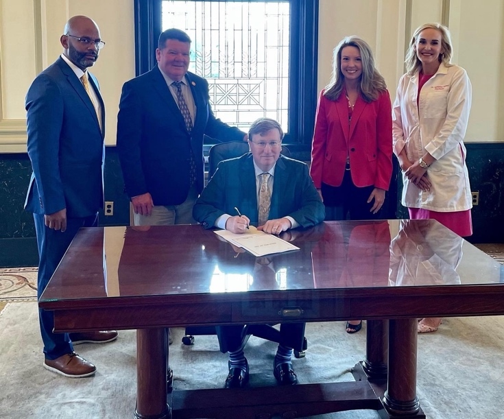 A group of people standing around a table Description automatically generated