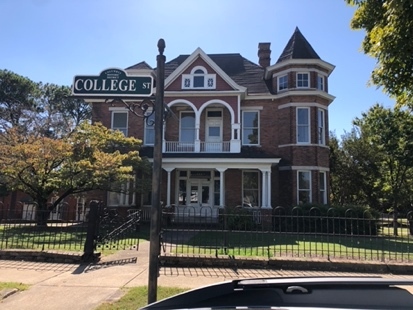 A house with a sign in front of it Description automatically generated