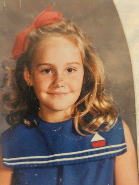 A young child in a blue dress Description automatically generated