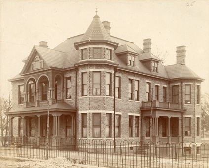 A large brick house with a fence Description automatically generated