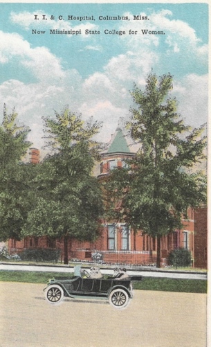 A large brick building with trees Description automatically generated