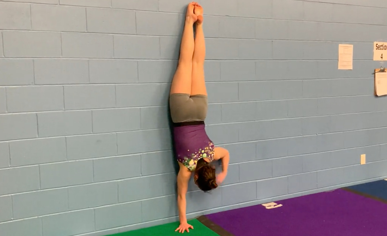 A person doing a handstand on a blue mat Description automatically generated with low confidence