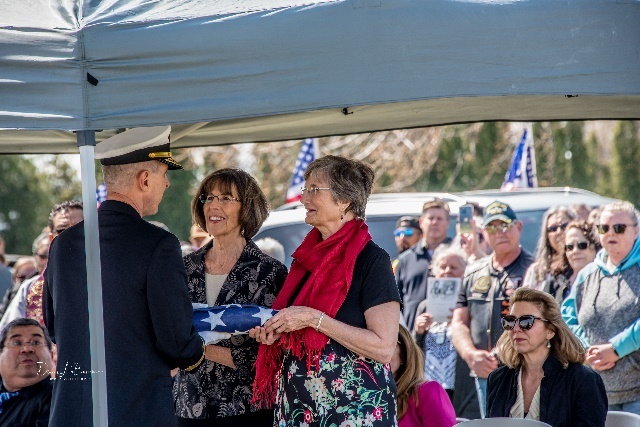 A person holding a flag with a person in a military uniform Description automatically generated