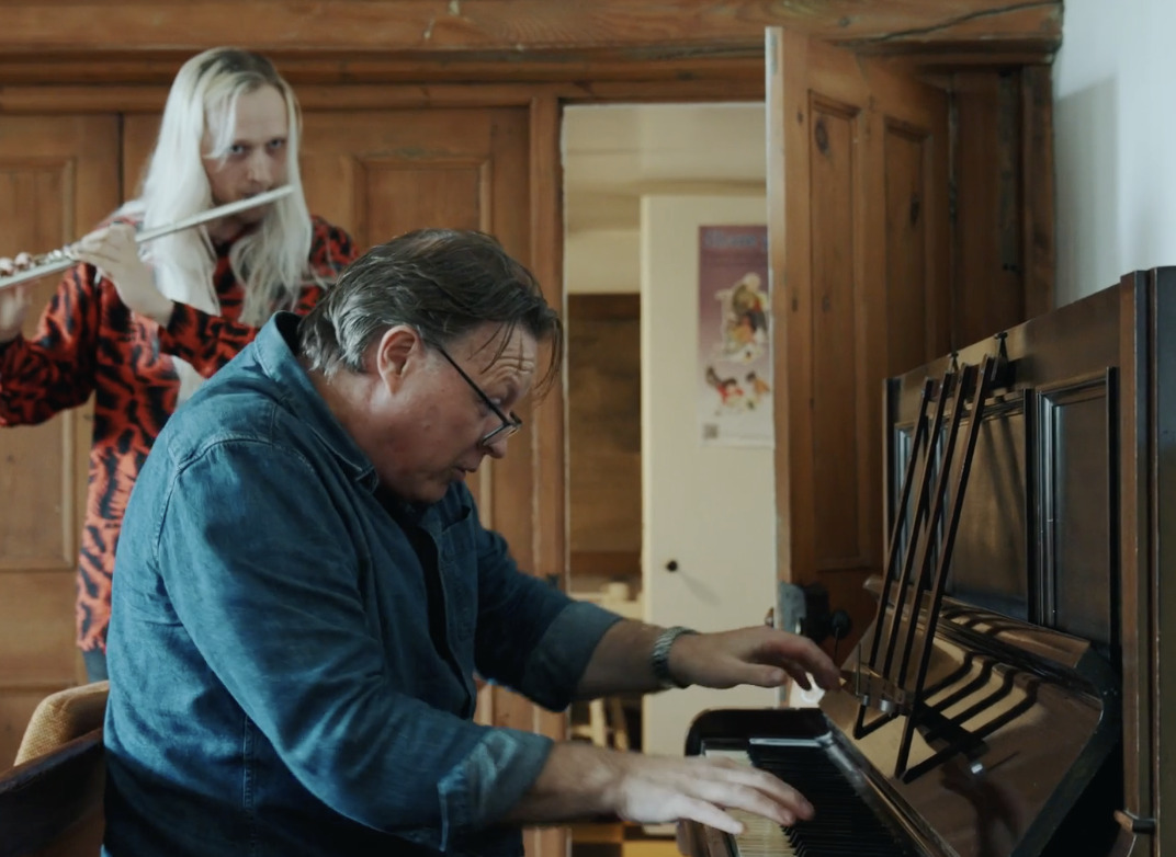 A person playing a piano with a person behind him AI-generated content may be incorrect.