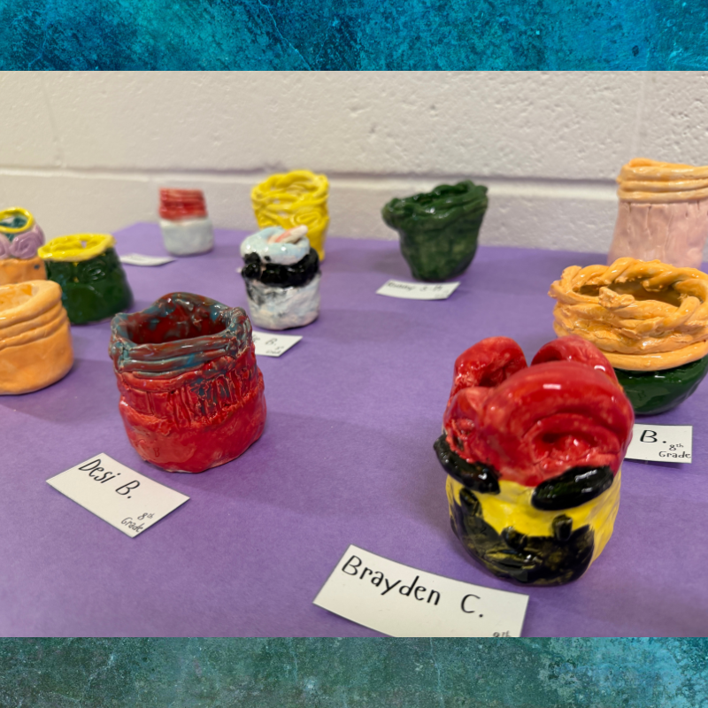 A collection of colorful, handmade ceramic pots displayed on a purple surface.