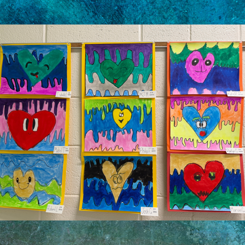 A wall display showcases colorful, hand-drawn heart artworks by students.