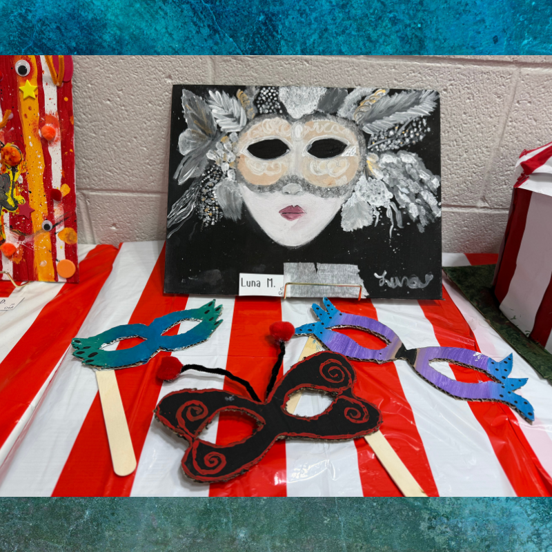 A display of colorful, handmade masks and a painting of a Venetian mask on a red and white striped tablecloth.