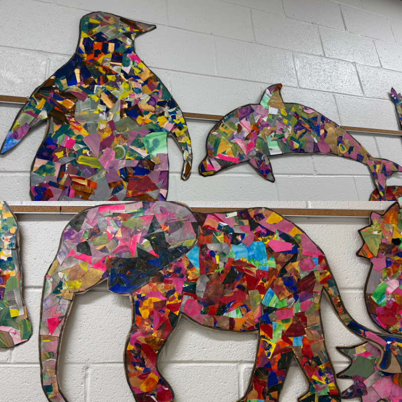 Colorful mosaic animal cutouts, including a penguin, dolphin, and elephant, adorn a white brick wall.