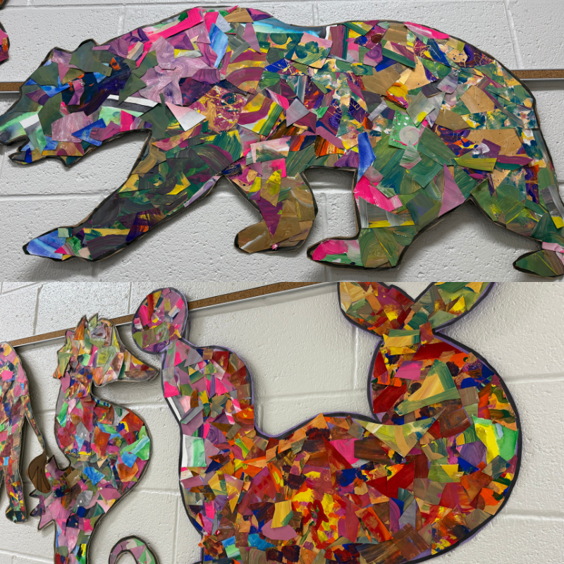 A colorful mosaic bear cutout hangs on a white brick wall.