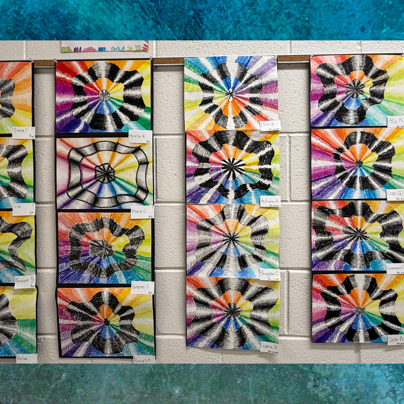 A wall display of colorful, radial pattern artwork created by students.