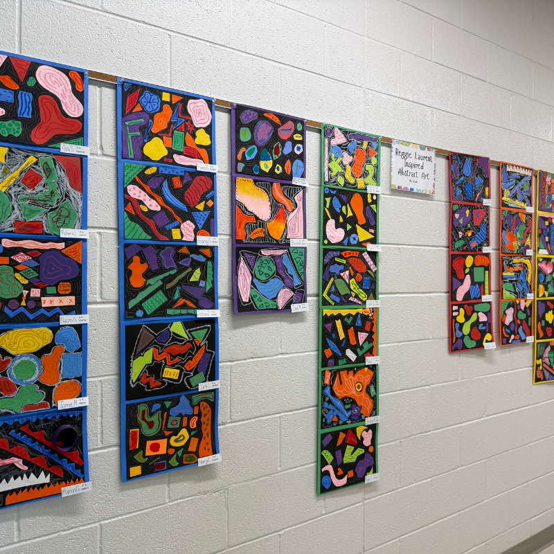 A hallway wall displays a vibrant collection of abstract art created by students.