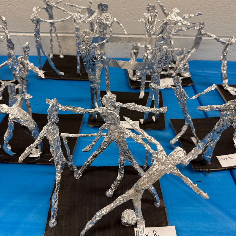 A collection of aluminum foil sculptures depicting human figures in various dynamic poses.
