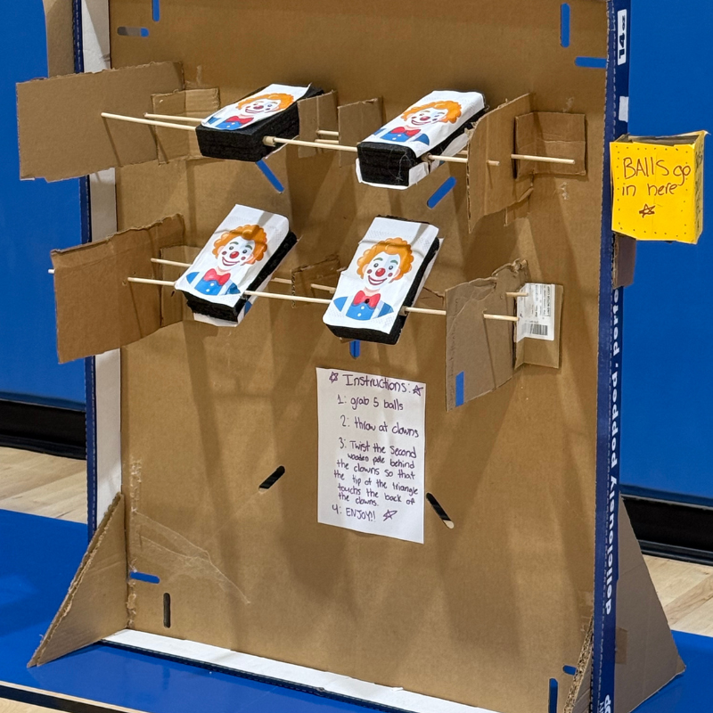 A handmade carnival game with clown targets and instructions for play.