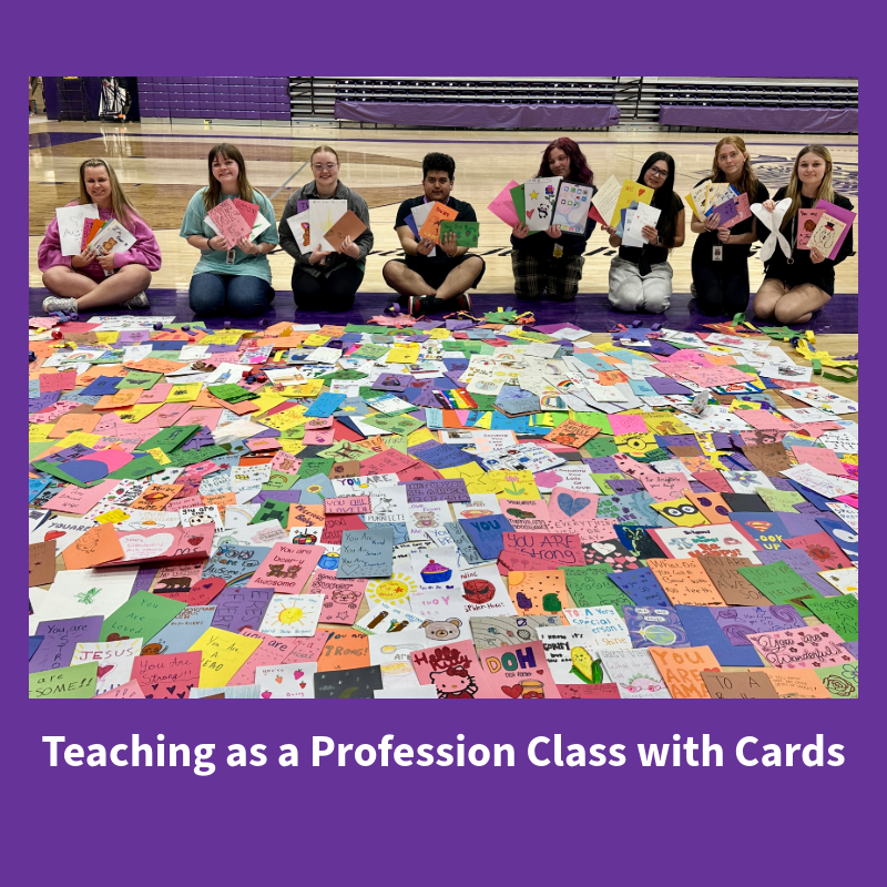 Students in a 'Teaching as a Profession' class sit on a gym floor surrounded by a vast collection of colorful, handmade cards.