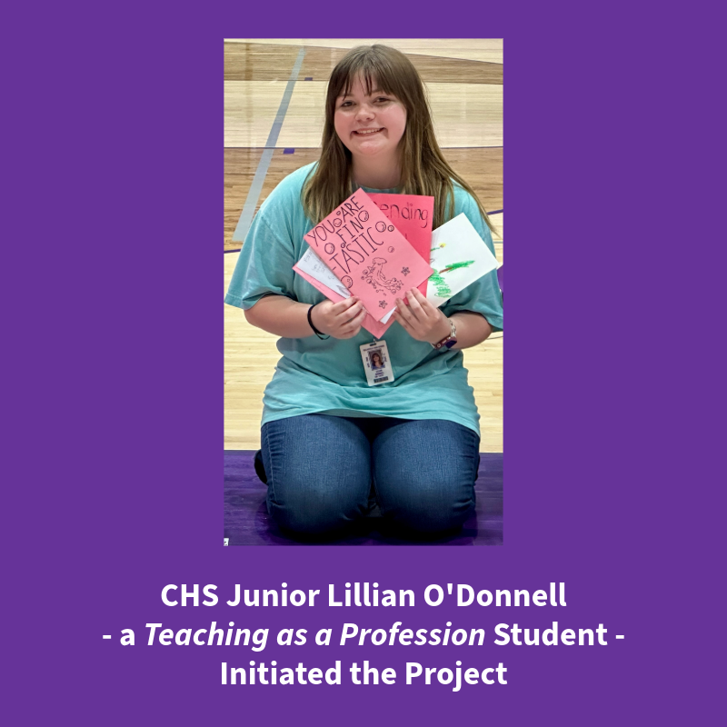 A young woman kneels on a purple mat, holding several handmade cards with positive messages.