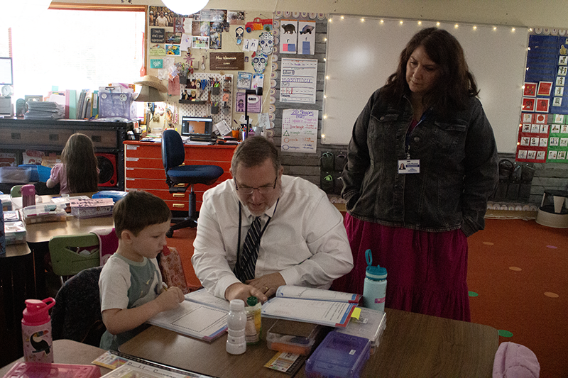 Matt Newell (center) and Jolie Phanton (right) help a student at Firwood Elementary.