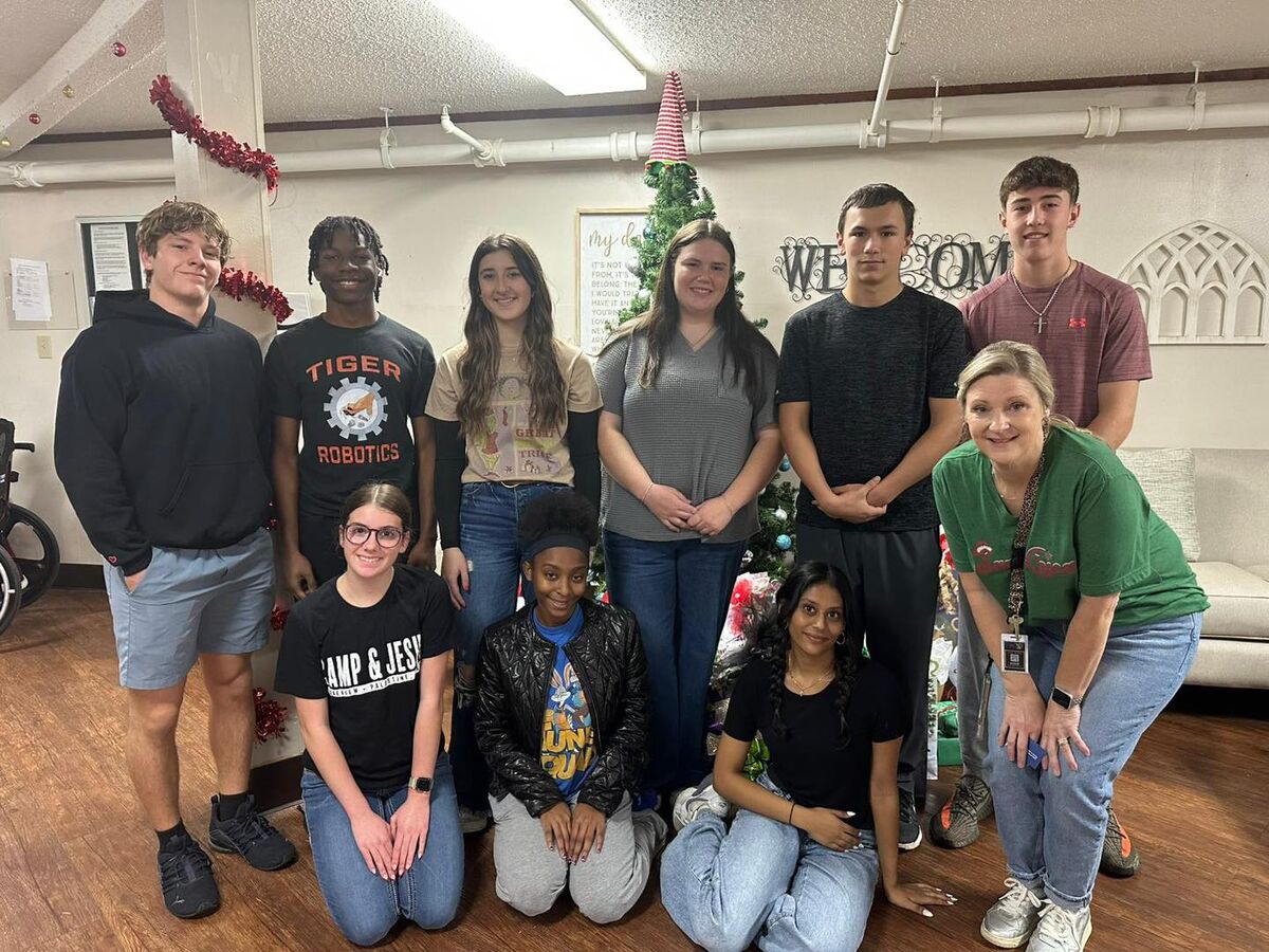 A group of students and their sponsor pose for a picture after delivering gifts to nursing home residents.