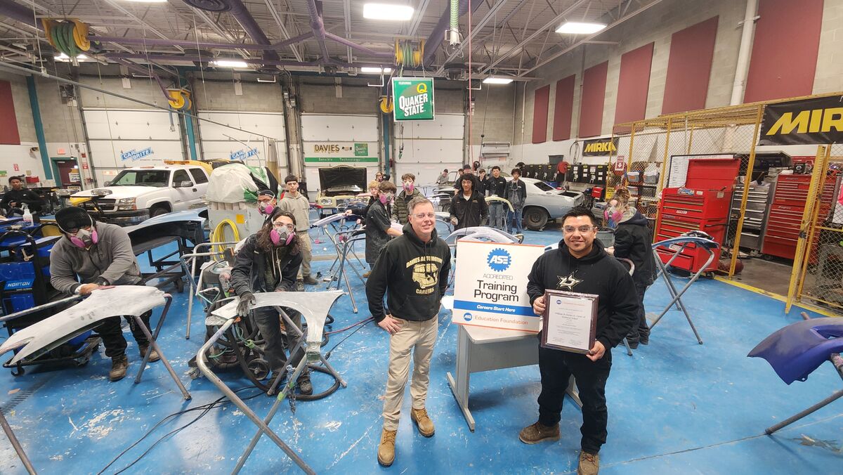 Mr. Guerra and Mr. Spillane pose with student working in class.