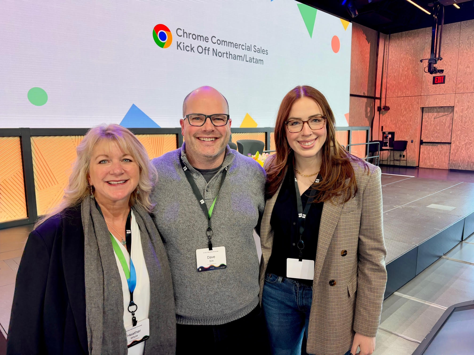 From left to right: Heather Whyte, Dave Stitt, and Kayla Frank stand together in a large conference room with a large screen behind them above a stage. The screen has a white background, the Google Chrome logo and says "Chrome Commercial Sales Kick Off Northam/Latam"