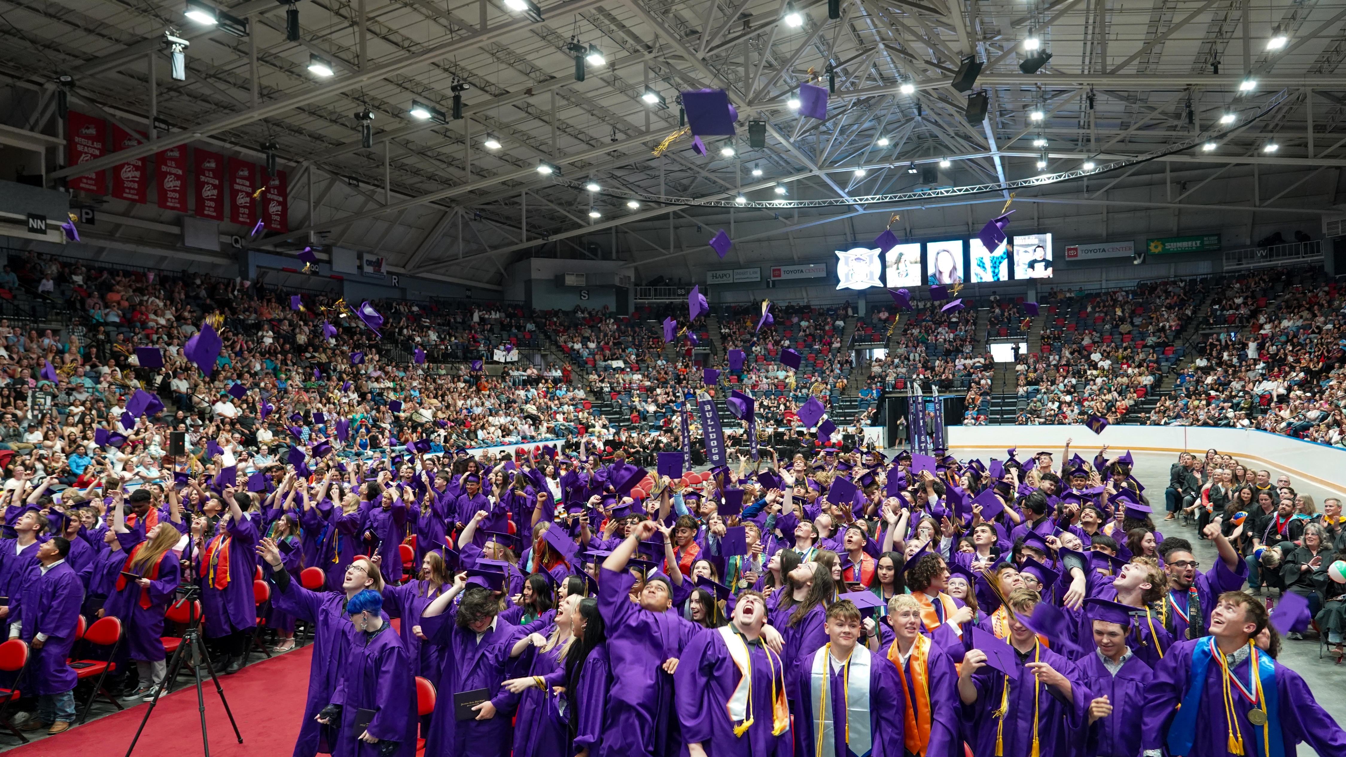 High school graduates throwing their graduation caps in the air